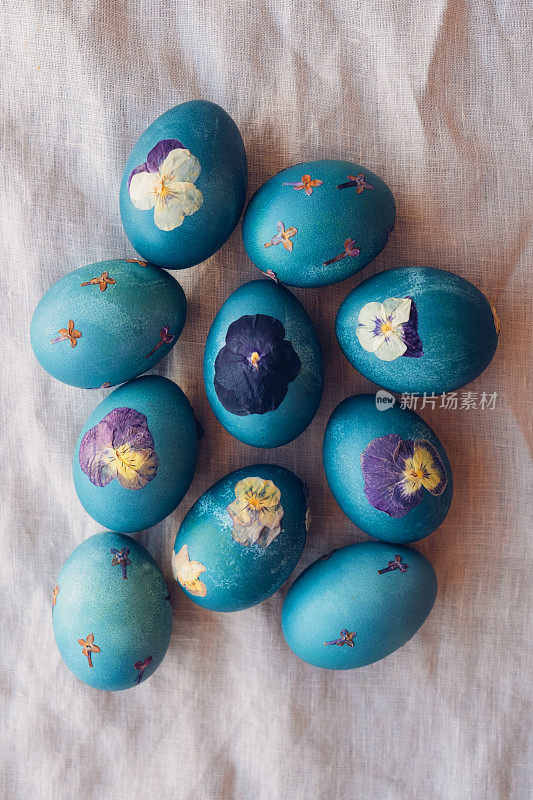 自然染色的青蓝压花复活节蛋在中性米色桌布背景。手工工艺，天然装饰。
