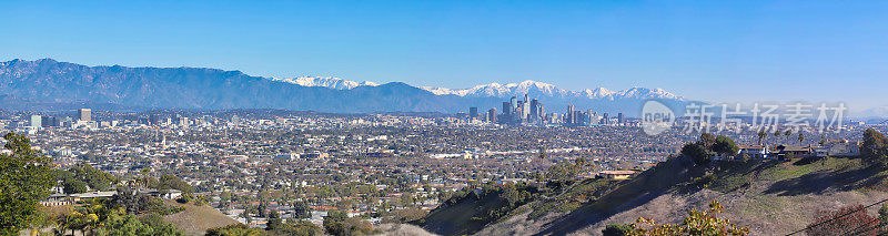 洛杉矶天际线全景图，背景是白雪覆盖的圣加布里埃尔山脉