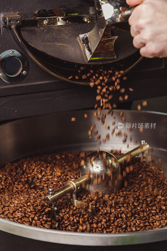 烘焙后的咖啡豆在烤箱的冷却板上搅拌均匀。工业咖啡豆烘焙。俯视图