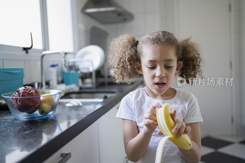小女孩在家里的厨房里吃水果