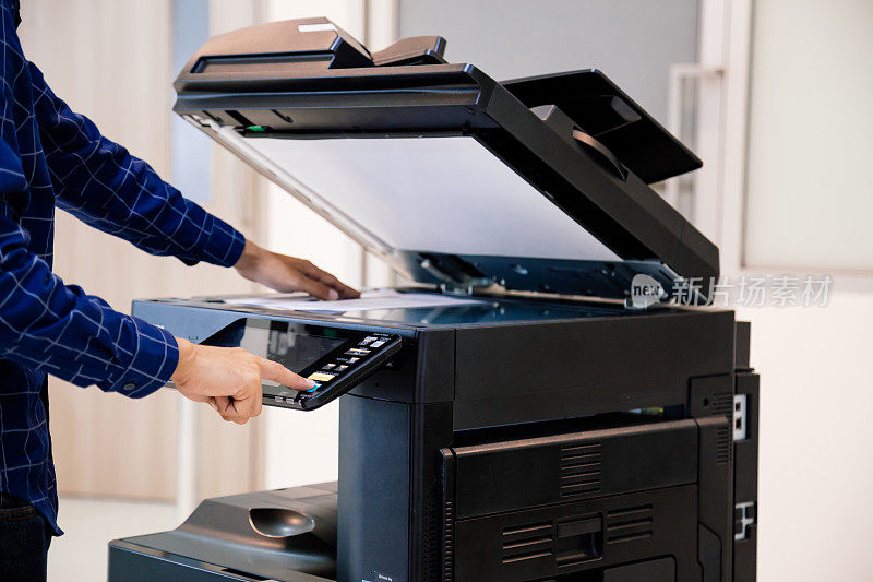 商务人士按下面板上的按钮，便可使用影印机或打印机在办公室打印或扫描文件。