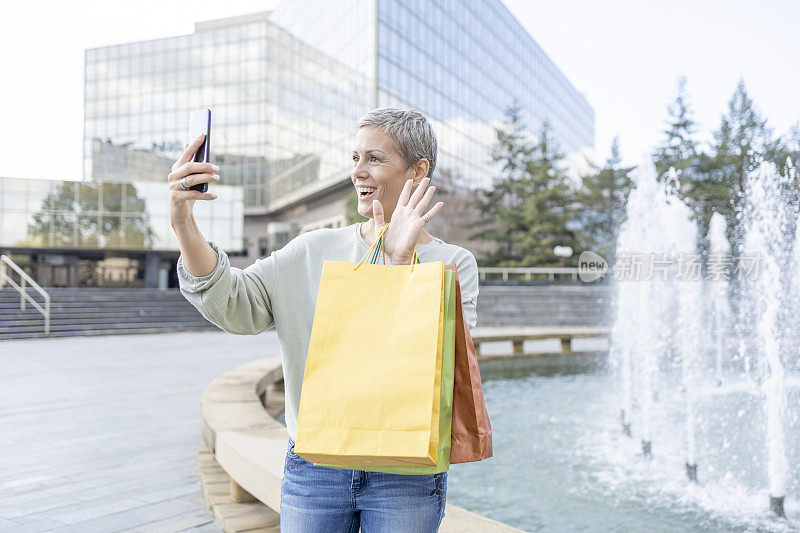 快乐的女人在购物后通过电话视频通话