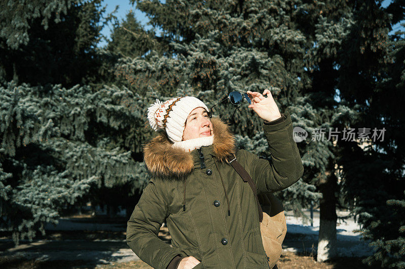 在冬季公园里，一名女子戴上了她的太阳镜