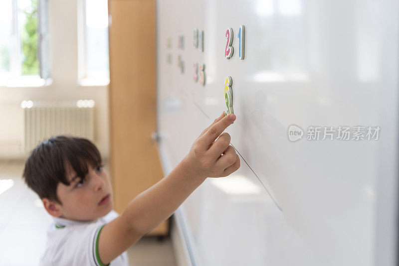 小学生穿着校服用白板上的磁性数字解数学题。