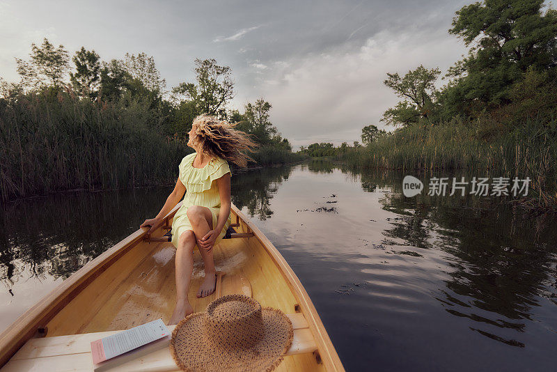 春日里，一个快乐的女人在湖上的船上摇着她的头发。