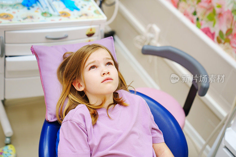 坐在牙科椅上的可爱少女害怕治疗她的牙齿。