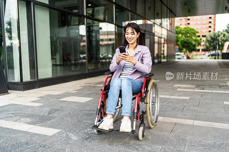 年轻美丽的亚洲女人坐在轮椅上在户外使用电话