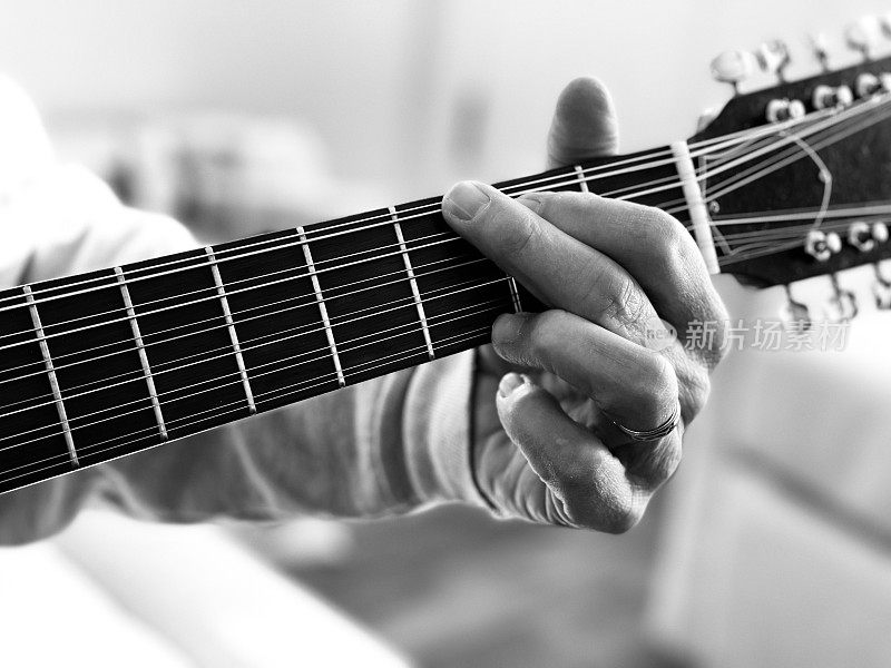 老人手弹12弦原声吉他的特写。