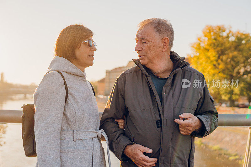 一对老年夫妇在日落时分在河边享受