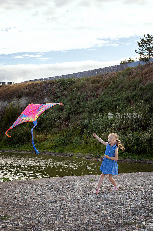 可爱的小女孩在海边玩风筝。风筝在风中飞翔。孩子在户外玩。