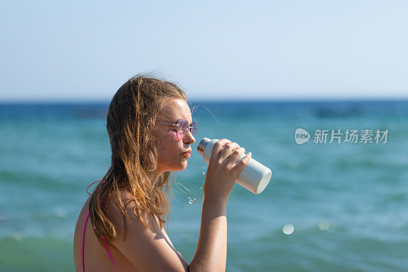 身着泳装的年轻女子喝水的特写镜头