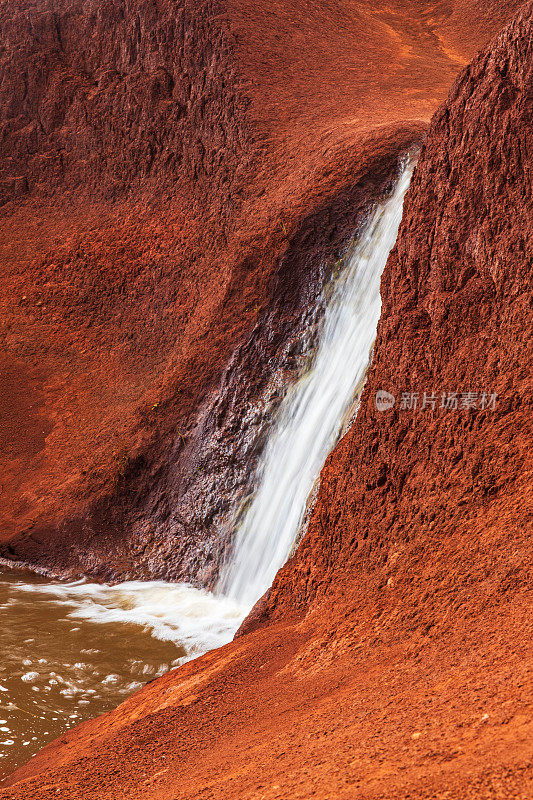 瀑布从鲜红色的火山岩上流过