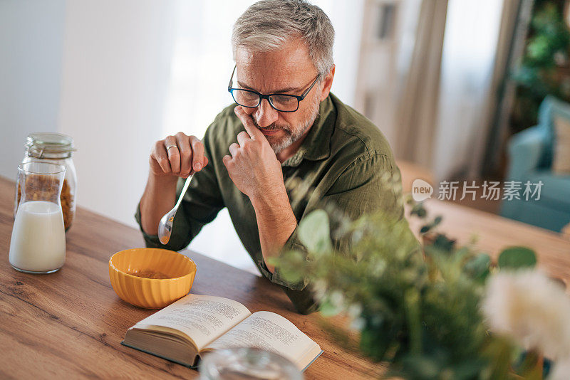 老人正在读书和吃早餐