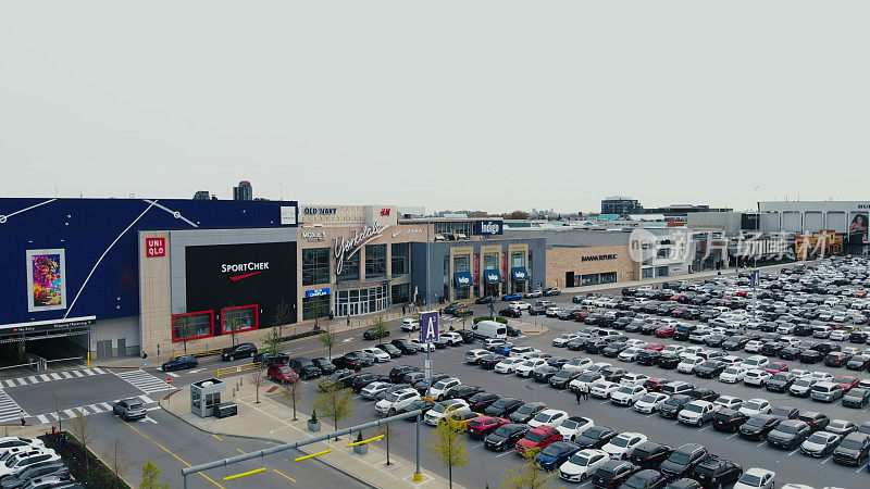 鸟瞰拥挤的商场停车场，购物中心熙熙攘攘挤满了消费者。零售中心，空间反映了高客流量。繁忙的周末购物场景，便利中心。