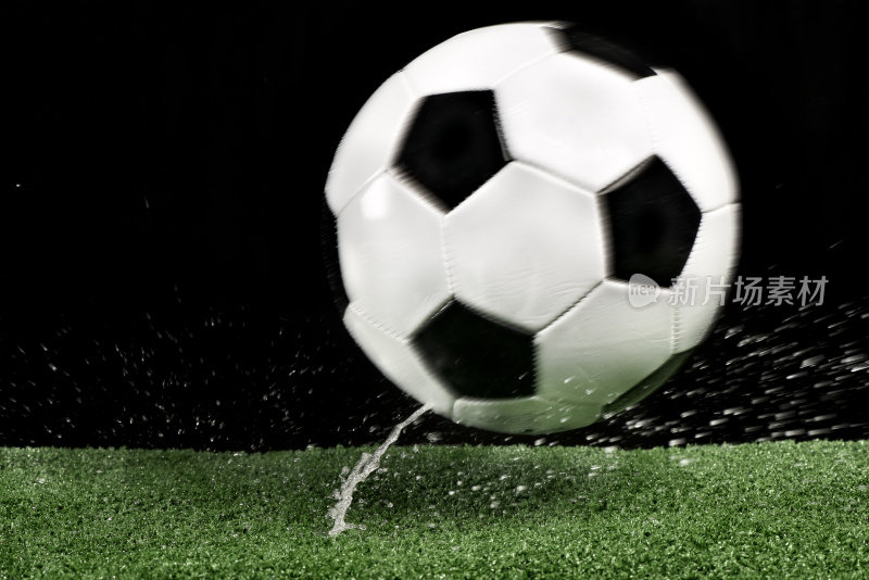 湿漉漉的足球在绿色的人造草地上弹跳