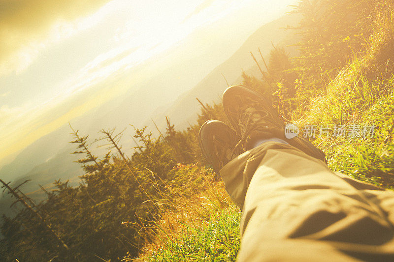 男人的腿在日落的山景中放松