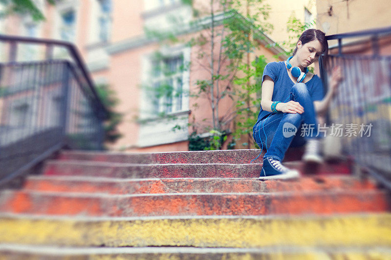 悲伤的女孩坐在外面的街道上