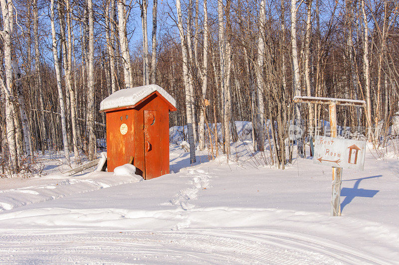 阿拉斯加偏远的外屋在雪与厕所标志