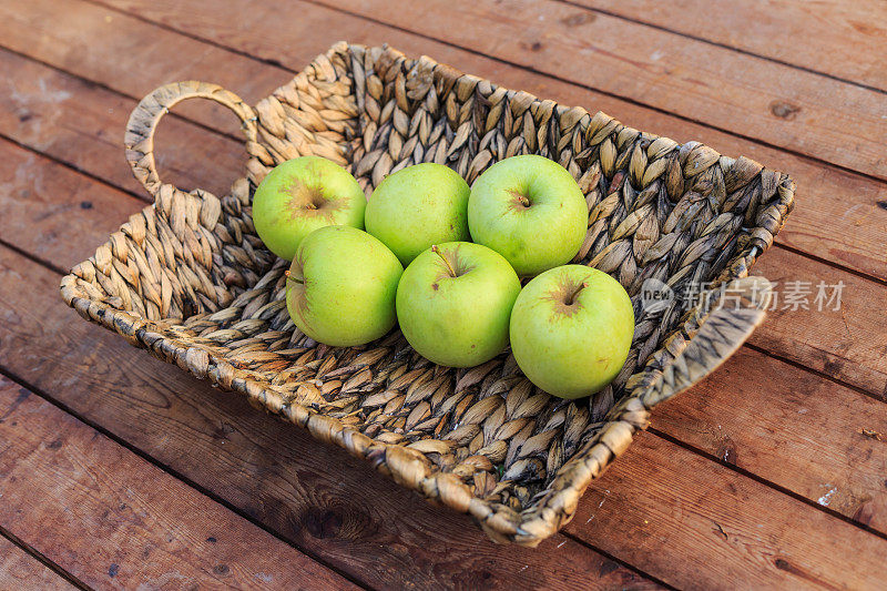 木桌上的篮子里放着青苹果