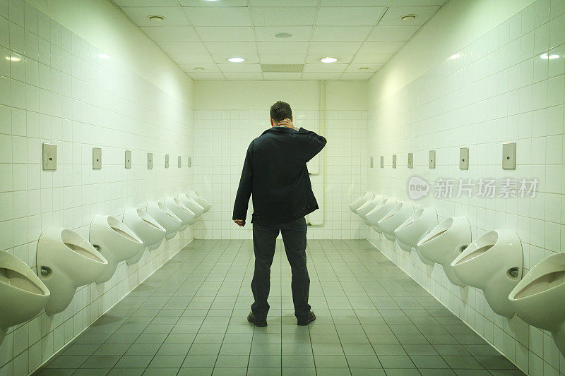 沉思的男人在荧光灯下上厕所