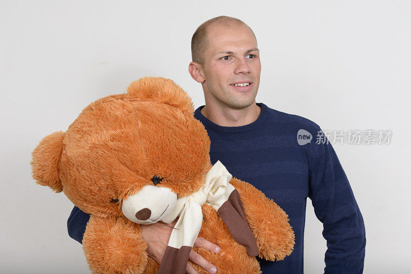 秃顶的年轻人抱着泰迪熊