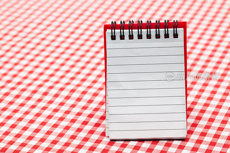 红色格子布桌布上的红色螺旋装订笔记本