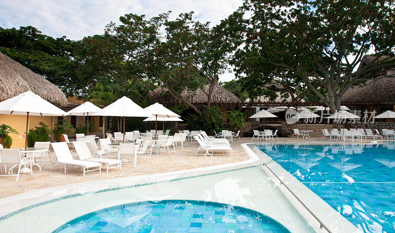 奢华的游泳池，白色雨伞映衬着郁郁葱葱的植被