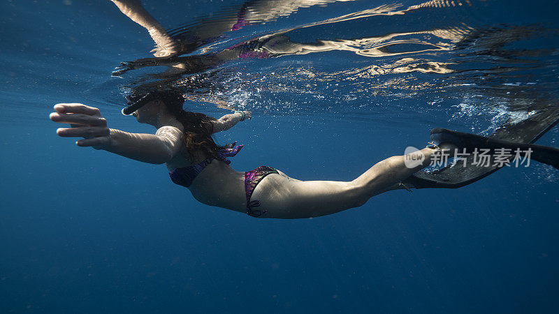 女性浮潜在深蓝色的海水比基尼