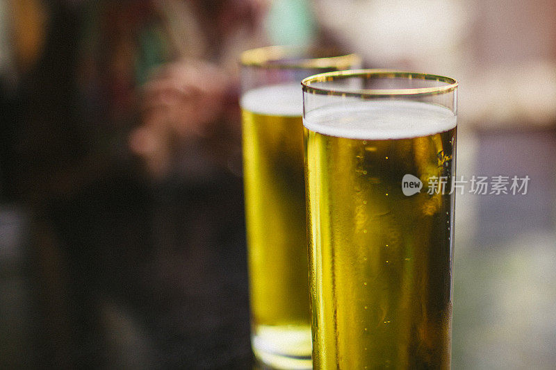 酒吧桌子上放着两只清爽的金色镶边啤酒杯。