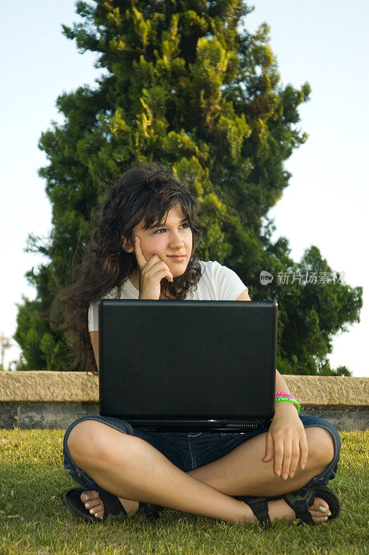 学生女孩在草地笔记本电脑上工作