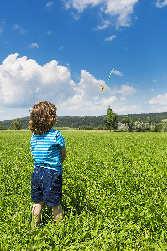 小男孩在草地上放他的玩具风筝