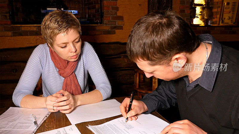 男女合作伙伴在咖啡馆签订合同