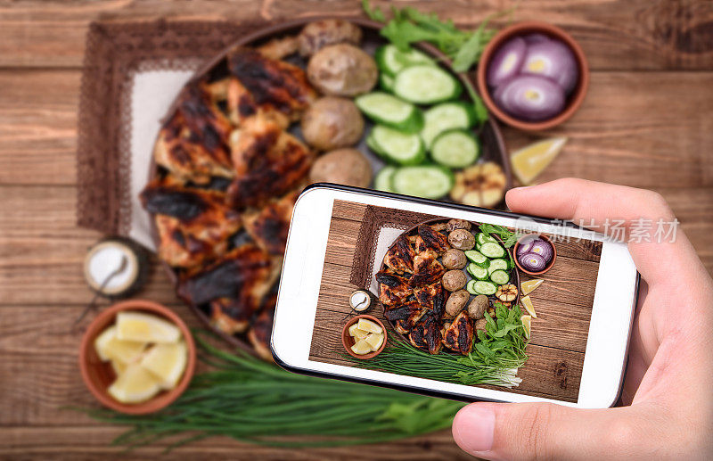 用智能手机拍鸡翅和烤土豆。