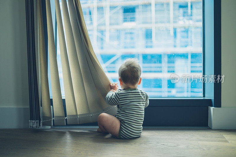 小婴儿在公寓里玩窗帘