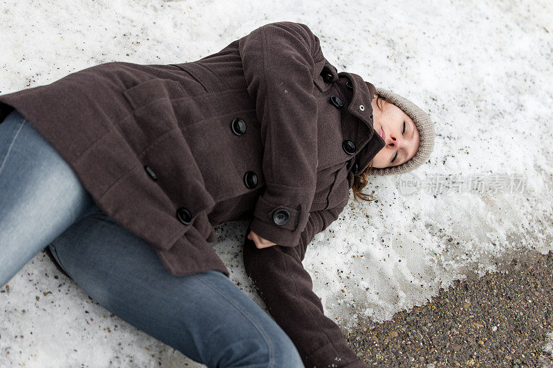 年轻女子无意识地躺在结冰的街道上
