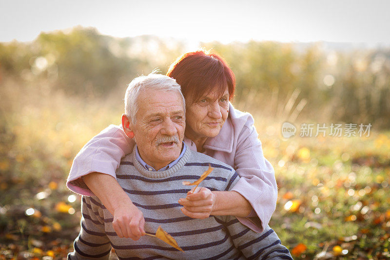 在阳光明媚的秋日，一对老年夫妇在大自然中