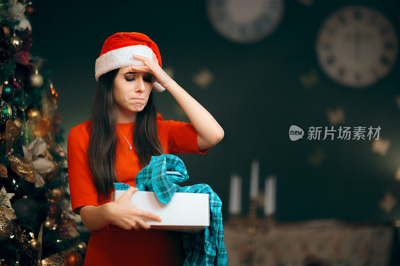 沮丧的女孩打开了一个糟糕的圣诞礼物发现里面的睡衣