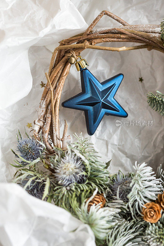 工艺，庆祝，装饰的概念。有一颗深蓝色的星星，用金色的细丝带系在圣诞花环上，把树枝连在一起