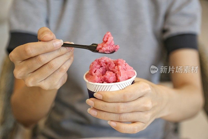 女人的手握杯有机冷冻酸奶冰淇淋外卖杯，健康的饮食理念。
