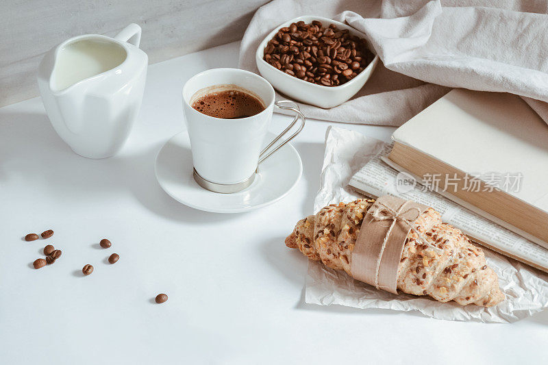 羊角面包，一杯加牛奶的咖啡，桌子上有一碗咖啡豆