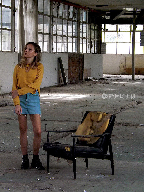 女孩待在废弃工厂的椅子旁边