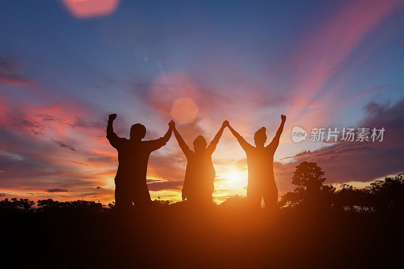 幸福家庭在日落中举手的剪影