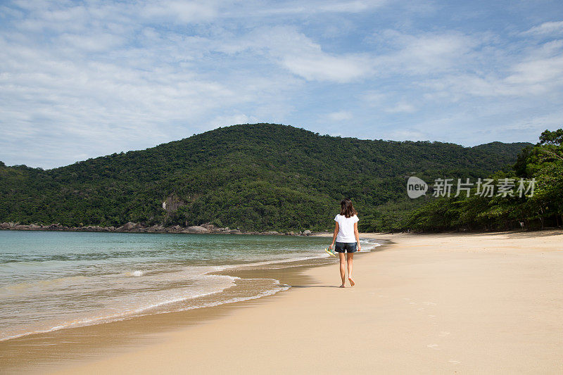 美丽的女人走在巴西荒芜的海滩上。