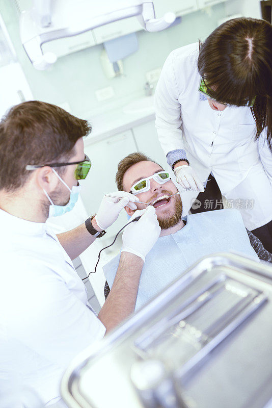 牙科医生和助理给病人做激光手术