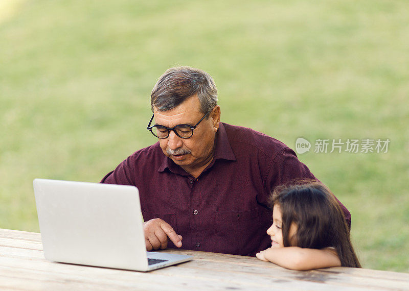 小女孩和爷爷一起用笔记本电脑