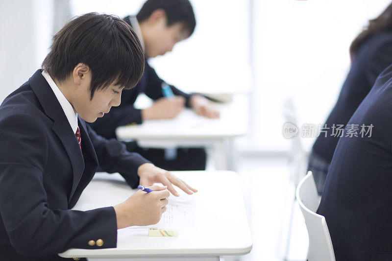 学校男孩在教室书桌上写作