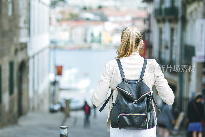 年轻女子背着背包走在欧洲的街道上