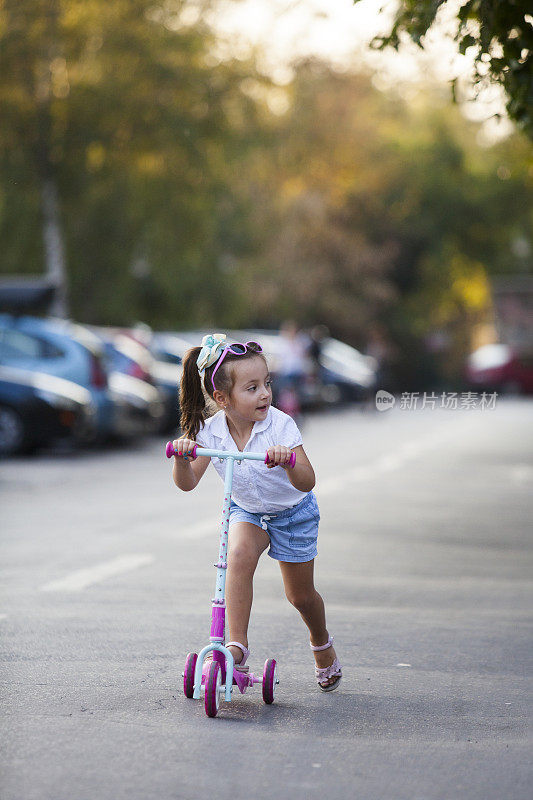 小女孩骑着踏板车