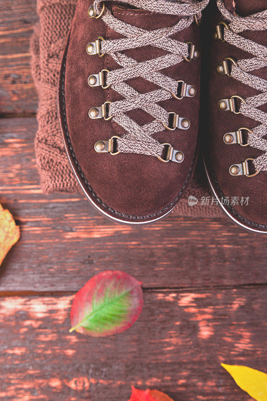 棕色人绒面革靴子与木制背景毛衣