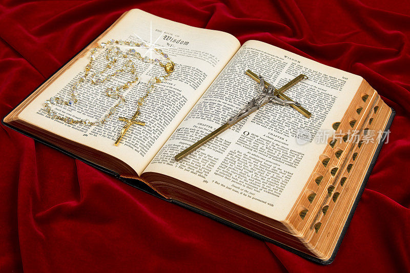 带念珠的《圣经》和带星星的十字架在红色天鹅绒上绽放